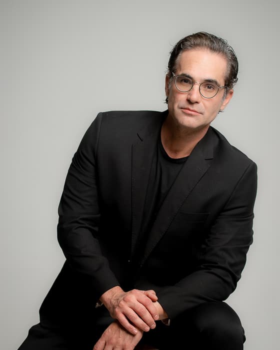 Dr. Daniel Botelho sentado, de terno preto
